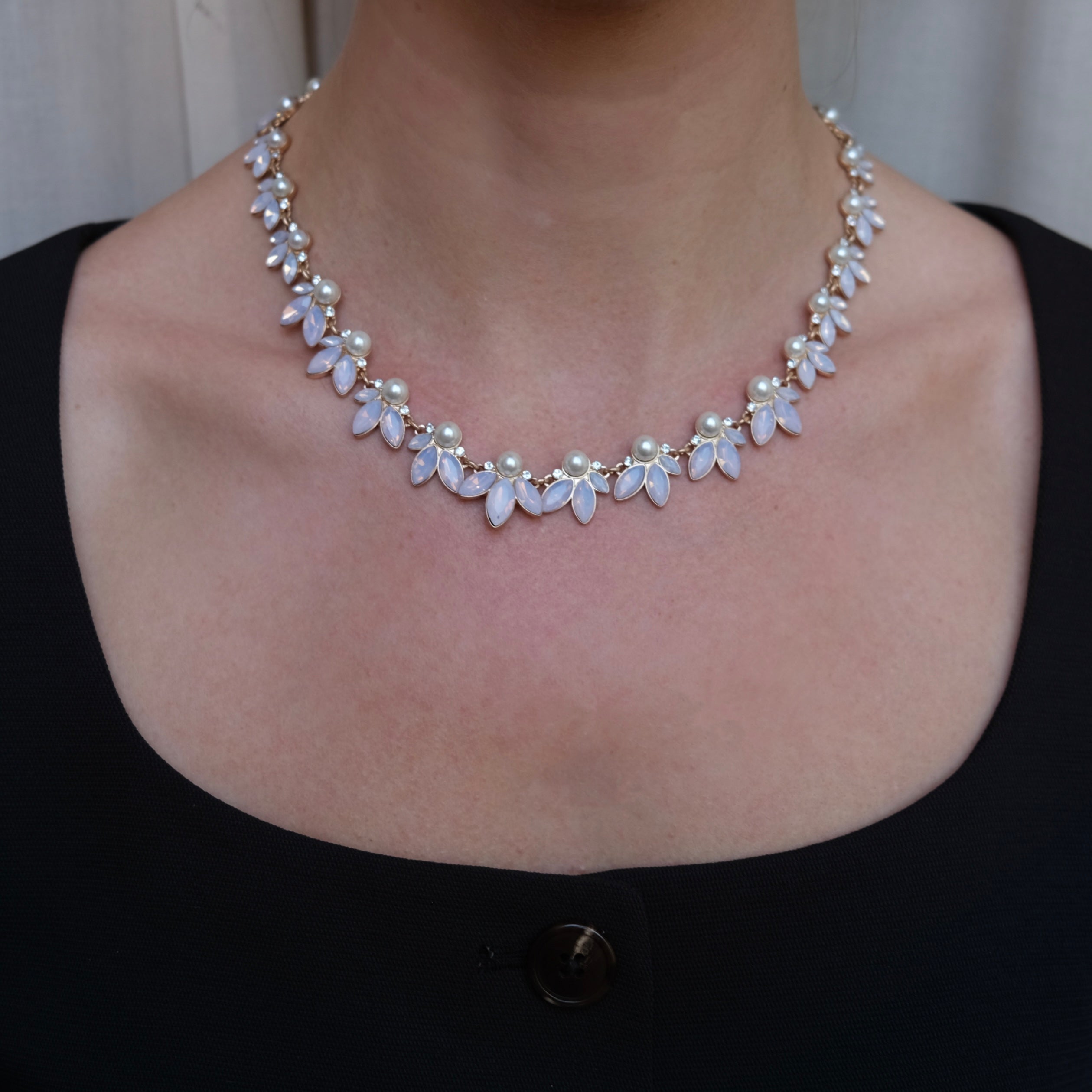 Necklace with floral design on a person wearing a black top.